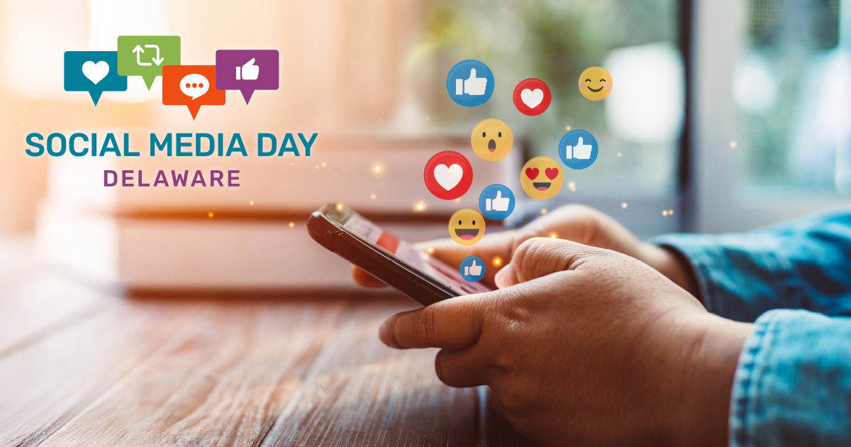 A person's hands hold a smartphone, with various social media reaction emojis like hearts, thumbs-up, and smiling faces floating above.